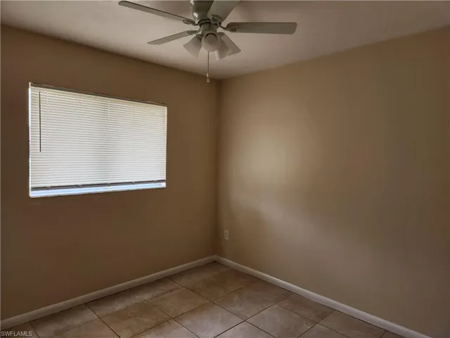 Unfurnished room with light tile patterned flooring and a ceiling fan