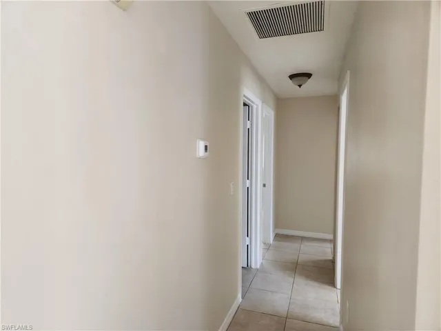 Corridor with light tile patterned flooring and baseboards