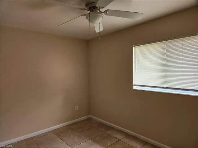 Empty room with light tile patterned floors and ceiling fan