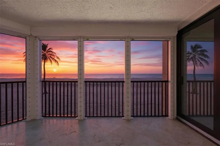 Screened balcony featuring view of water and beach