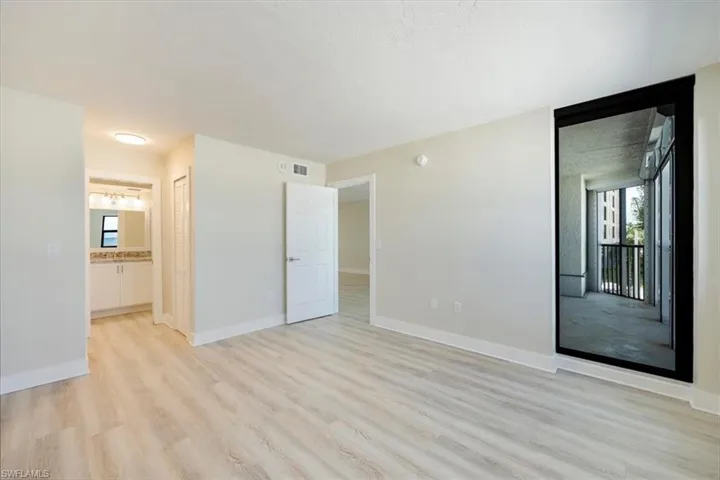 Bedroom with connected bathroom and light woo-style floors
