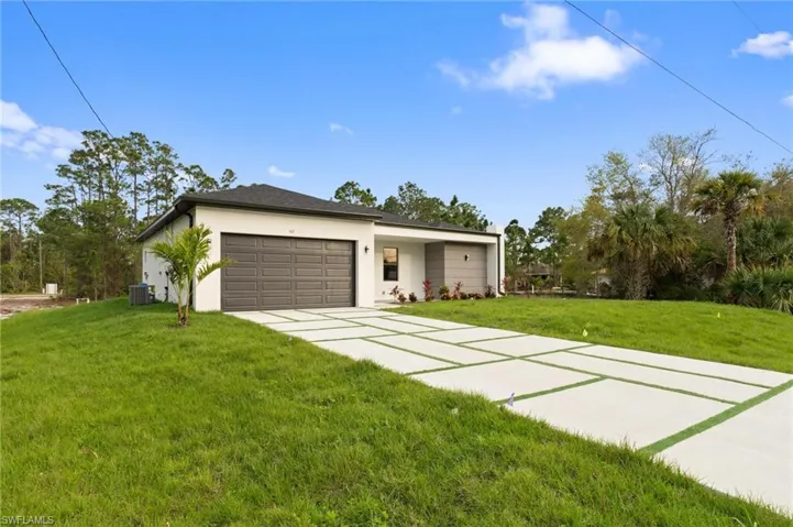 View of front of home featuring stucco siding, driveway, a front yard, an attached garage, and central AC unit