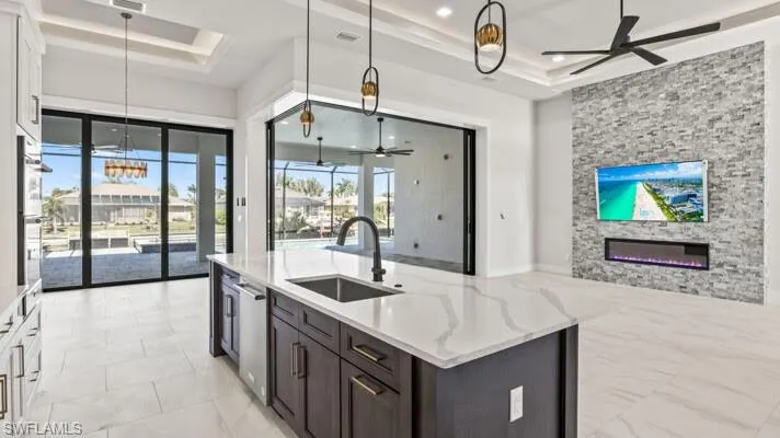 Kitchen with stainless steel appliances, white cabinetry, hanging light fixtures, and a kitchen island with sink