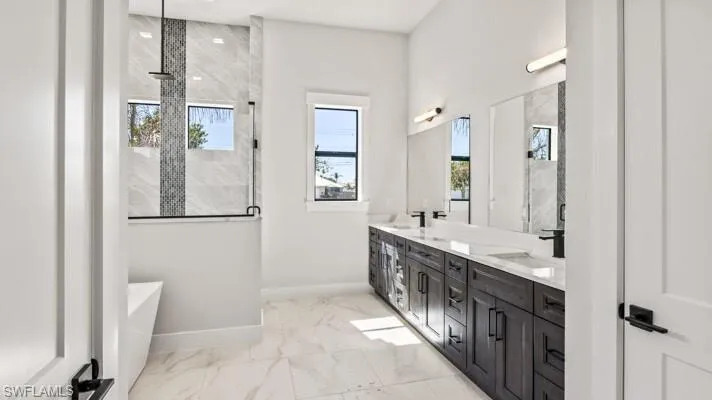 Primary ensuite bath with soaking tub and walk in glass enclosed shower multiple shower heads and bench seating.