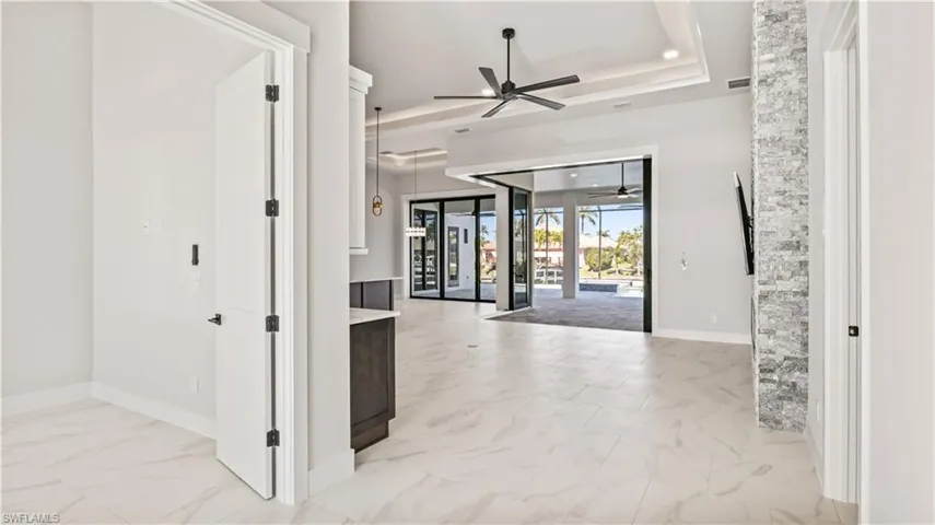 Foyer entrance with a raised ceiling, ceiling fan, and french doors