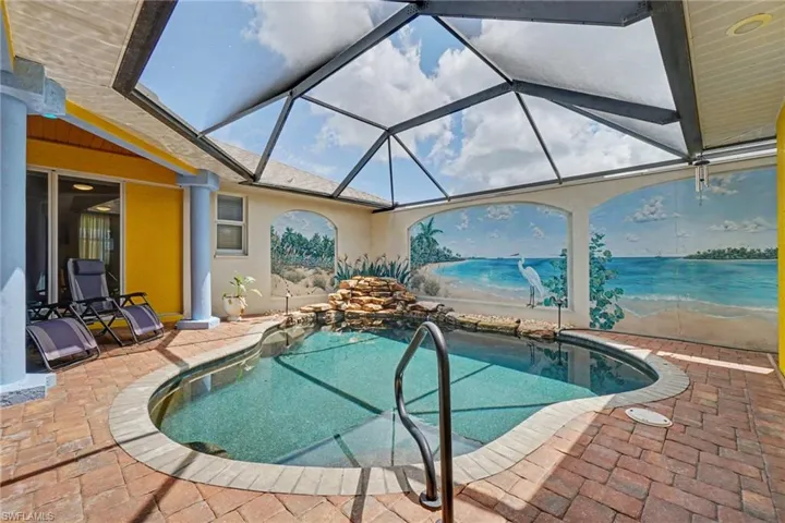 Screened-in patio featuring a built-in swimming pool with a rock waterfall feature, brick paver decking, and a custom mural wall