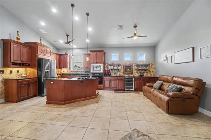Spacious kitchen and entertaining area featuring a large center island, recessed lighting, tile flooring, and vaulted ceilings