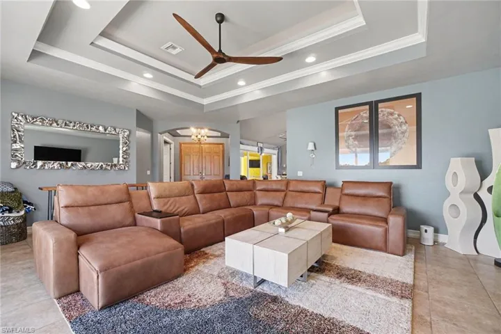 Tray ceiling with recessed lighting and a ceiling fan, complemented by tile flooring