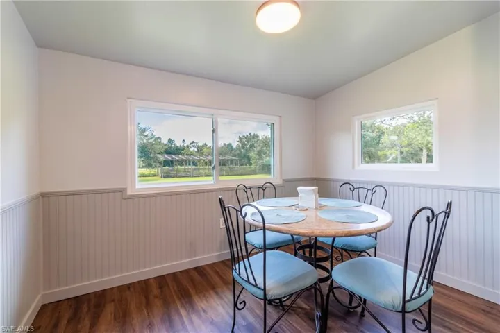 Dining space with dark wood-type flooring, vaulted ceiling, and a wealth of natural light