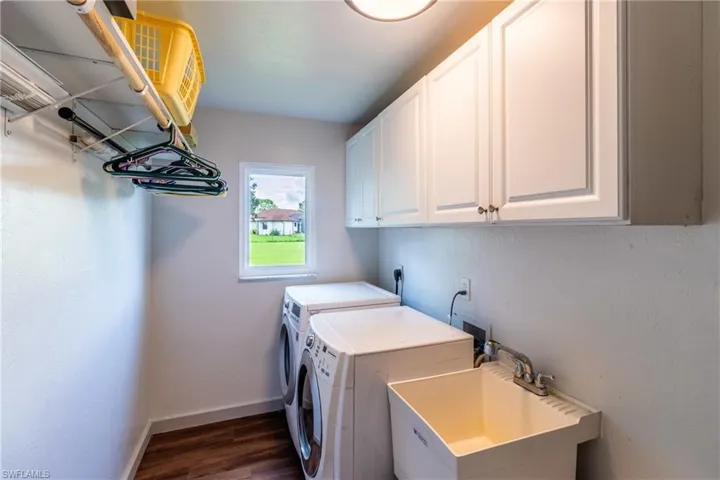 Laundry area with cabinets, sink, dark hardwood / wood-style flooring, and separate washer and dryer