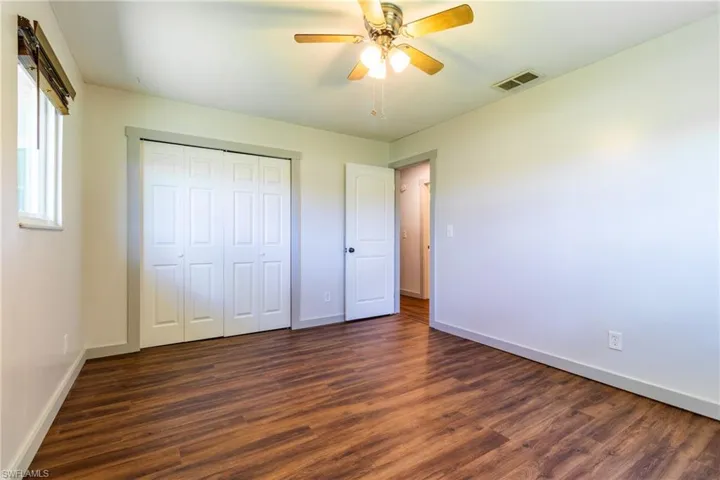 Unfurnished bedroom with a closet, ceiling fan, and dark wood-type flooring