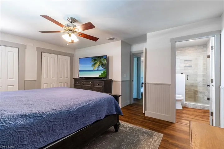 Bedroom featuring multiple closets, wood-type flooring, ensuite bath, and ceiling fan