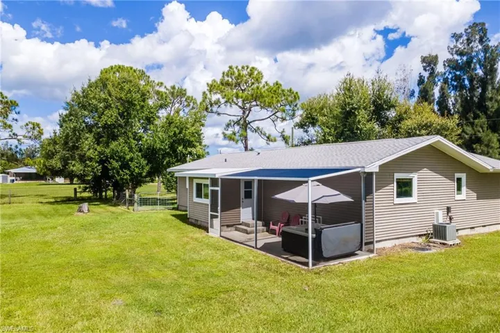 Rear view of house featuring a patio, central AC, and a lawn