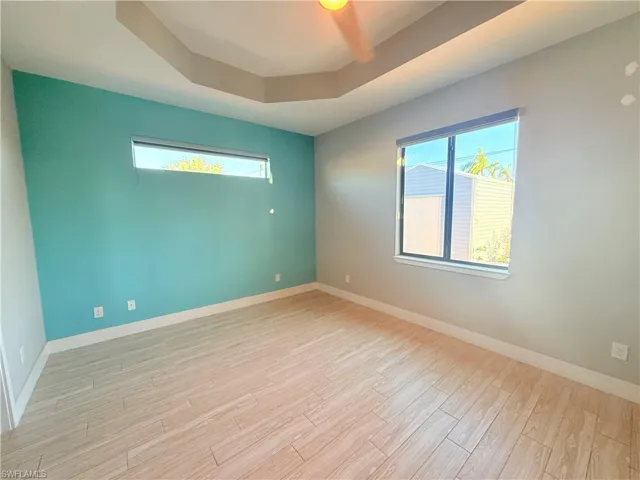 Spare room featuring a tray ceiling and light wood-style floors