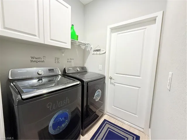Laundry area featuring washing machine and clothes dryer, cabinet space, and light wood finished floors