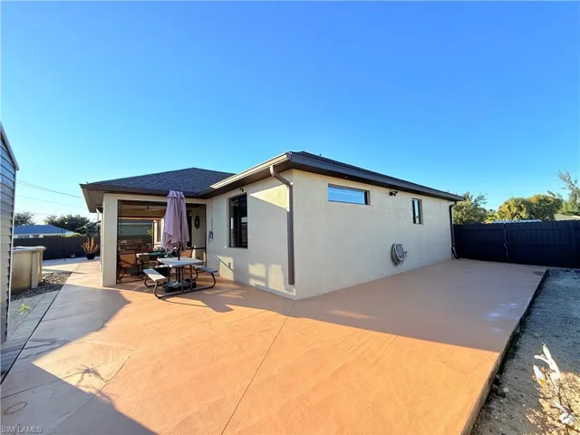 Back of house with a fenced backyard, a patio, stucco siding, outdoor dining space, and roof with shingles