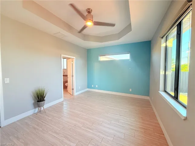 Spare room featuring a raised ceiling, light wood finished floors, and a ceiling fan