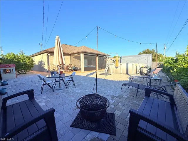 View of patio featuring a fire pit, outdoor dining space, and a sunroom
