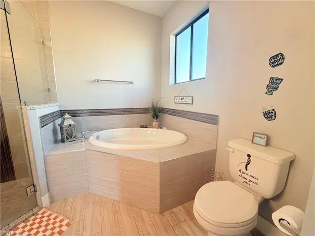 Full bath with a bath, a shower stall, and wood finished floors