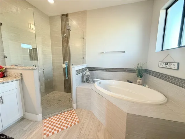 Full bath with a shower stall, a garden tub, vanity, recessed lighting, and light wood-style floors