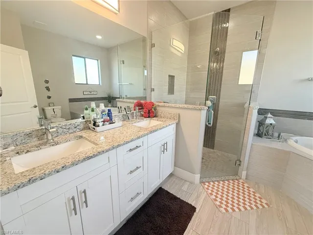 Full bath with a shower stall, double vanity, a bath, and light wood finished floors