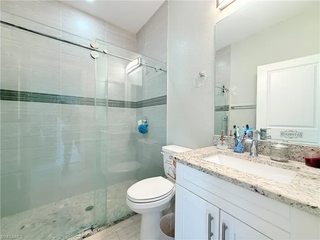 Bathroom with vanity, a stall shower, and a textured wall