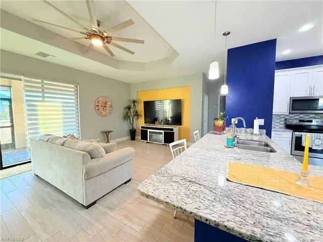 Living area featuring a ceiling fan, light wood-style flooring, and a tray ceiling
