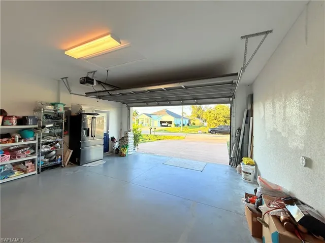 Garage featuring a textured wall, high end fridge, and a garage door opener