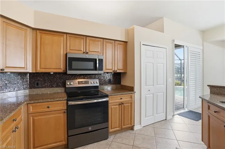 Kitchen featuring wood cabinetry, granite-style countertops, mosaic tile backsplash, and stainless steel appliances