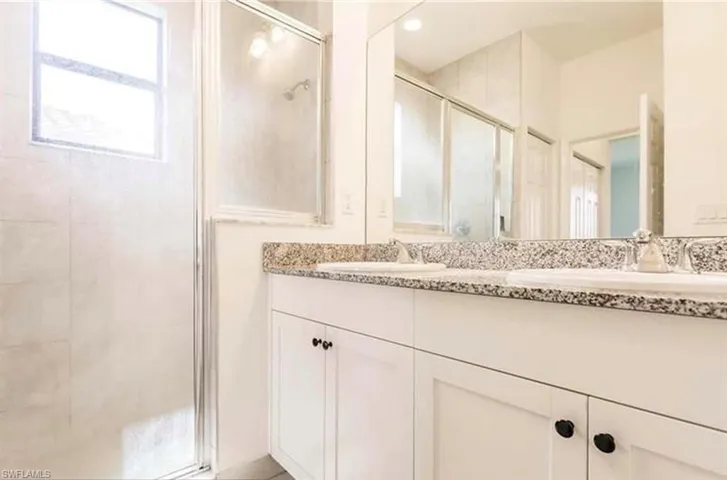 Bathroom featuring a shower stall and double vanity