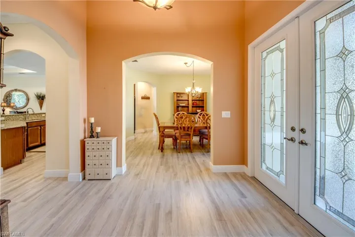 Entryway featuring light wood finished floors, hanging lights, french doors, and arched walkways