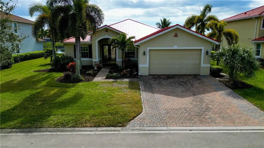 View of front of property with a front yard, stucco siding, decorative driveway, and an attached garage