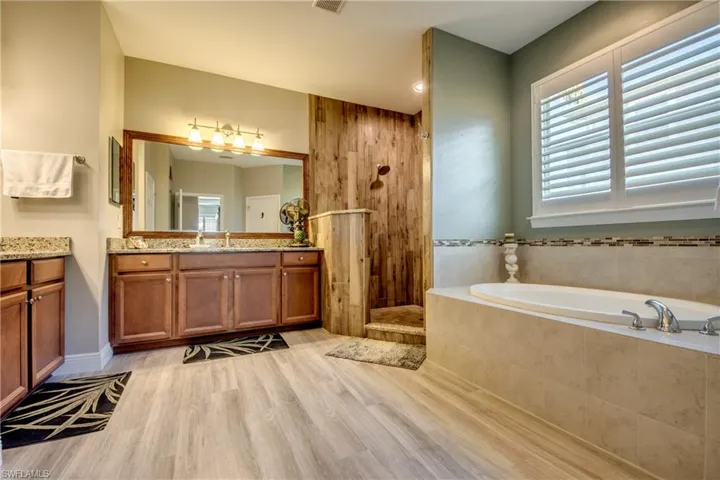 Full bathroom with vanity, a bath, light wood finished floors, a walk in shower, and plenty of natural light