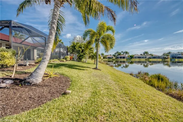 View of grassy yard featuring a sunroom, a lanai, a residential view, and a water view