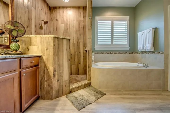 Full bathroom featuring vanity, a bath, light wood-style flooring, and a walk in shower
