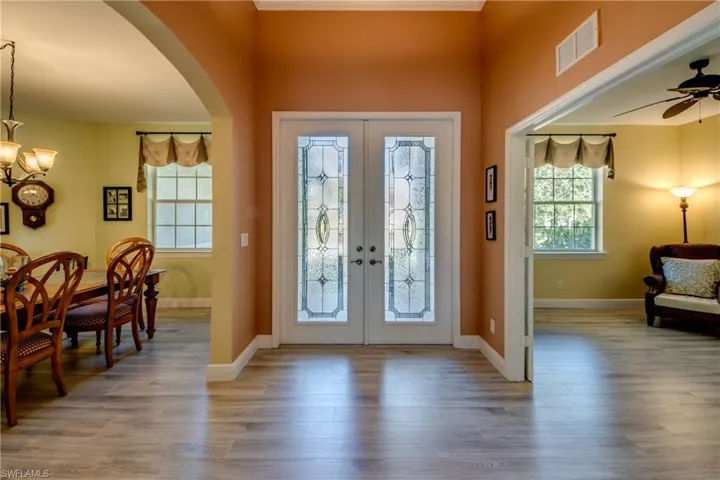 Foyer with arched walkways, light wood-type flooring, french doors, and a ceiling fan