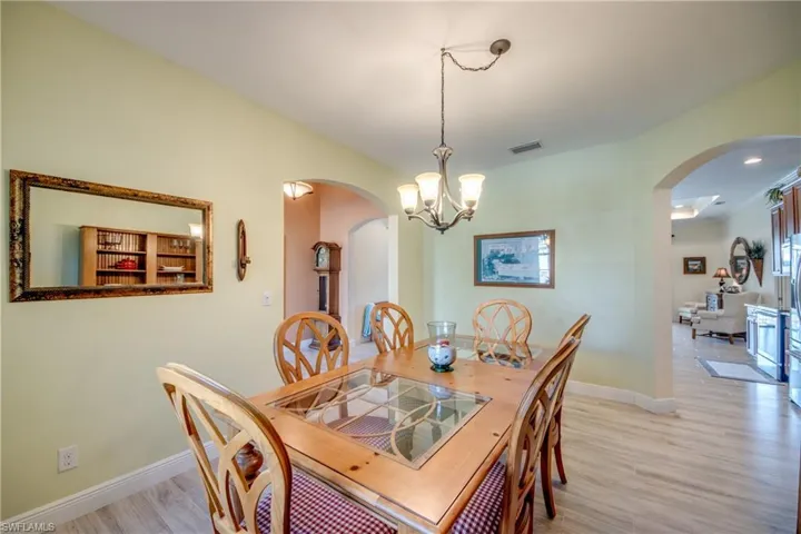 Dining area featuring arched walkways, a chandelier, and light wood finished floors