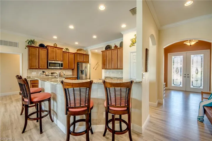 Kitchen with a breakfast bar, wood finish cabinets, tasteful backsplash, french doors, and arched walkways