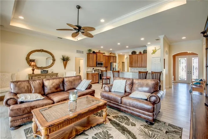 Living room featuring arched walkways, ornamental molding, light wood finished floors, recessed lighting, and french doors