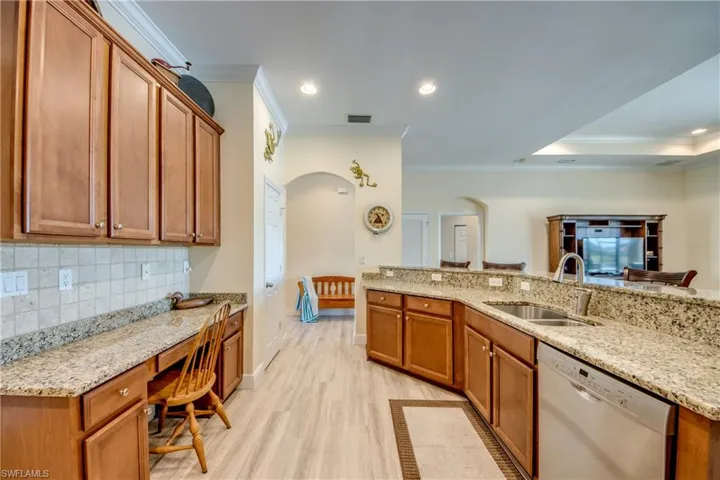 Kitchen featuring wood finish cabinets, dishwasher, light stone counters, ornamental molding, and recessed lighting