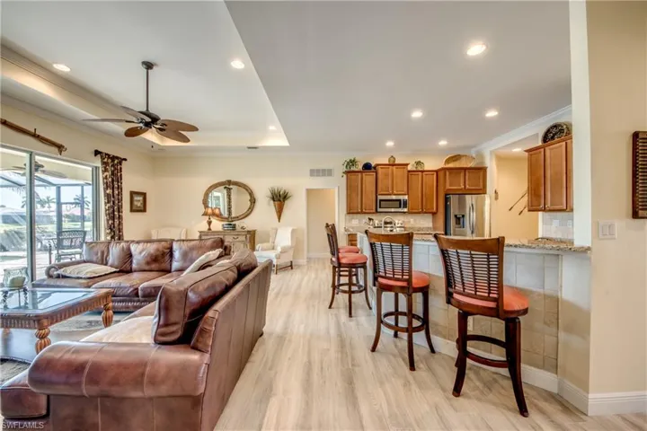 Living room featuring light wood-style floors, ceiling fan, recessed lighting, and crown molding