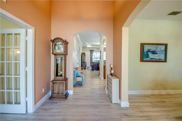 Corridor with arched walkways and light wood finished floors