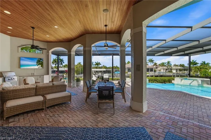 Resort-style outdoor space with a newly resurfaced & retiled pool with travertine coping & multi-color LED lights, spa, outdoor kitchen, lounging area with 65 inch TV & pool bath, all overlooking the spectacular water views.