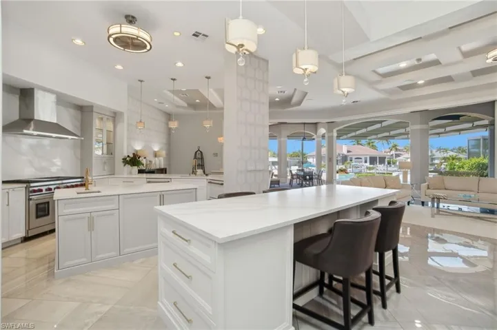 2026 newly renovated chef’s kitchen with new Serena and Lily wallpaper offers white quartz counters, custom white cabinetry with oversized eat-in island.