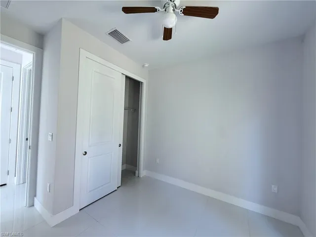 Unfurnished bedroom with a closet, light tile patterned floors, and ceiling fan