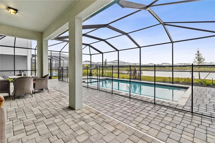 Screened lanai featuring a paver patio, integrated swimming pool, and a black safety fence