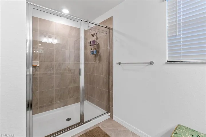 Glass-enclosed shower featuring large format wall tiles and a polished chrome frame