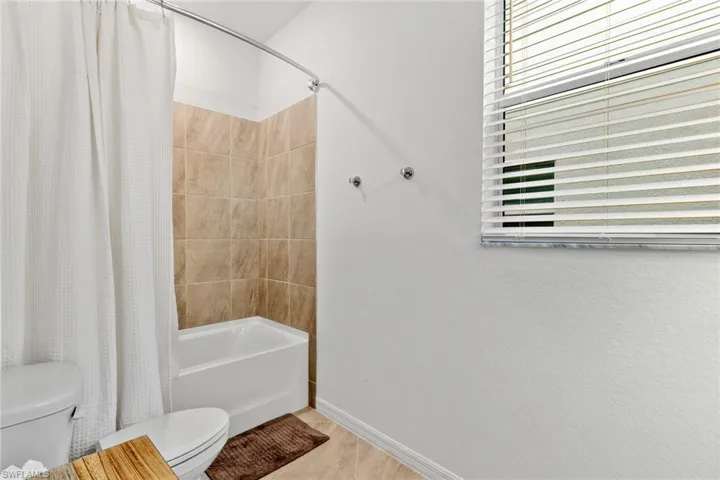 Bathroom featuring a white bathtub, ceramic tile surround, and a toilet
