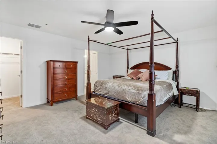 Spacious room featuring light gray carpeting, a ceiling fan with integrated lighting, and a white interior door leading to a closet with wire shelving
