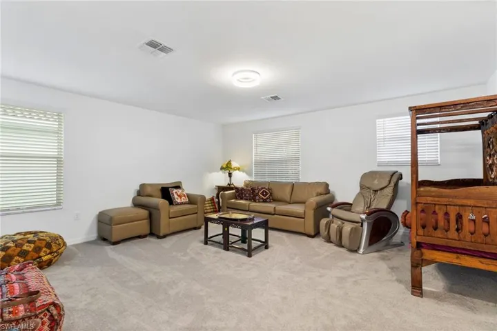 Spacious room featuring light gray carpeting, multiple windows with blinds, a recessed ceiling light, and white painted walls
